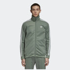 Person wearing a green Adidas tracksuit on a white background