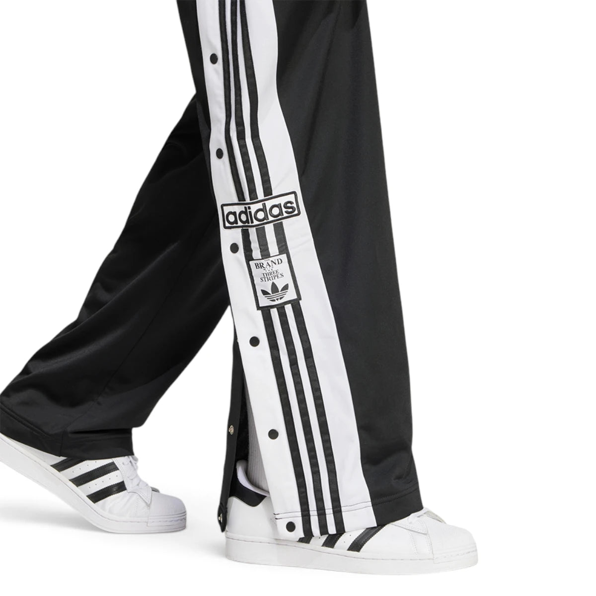 Detailed close-up angle focusing on the branded snap-button hardware and the classic woven Adibreak label positioned near the lower hem.