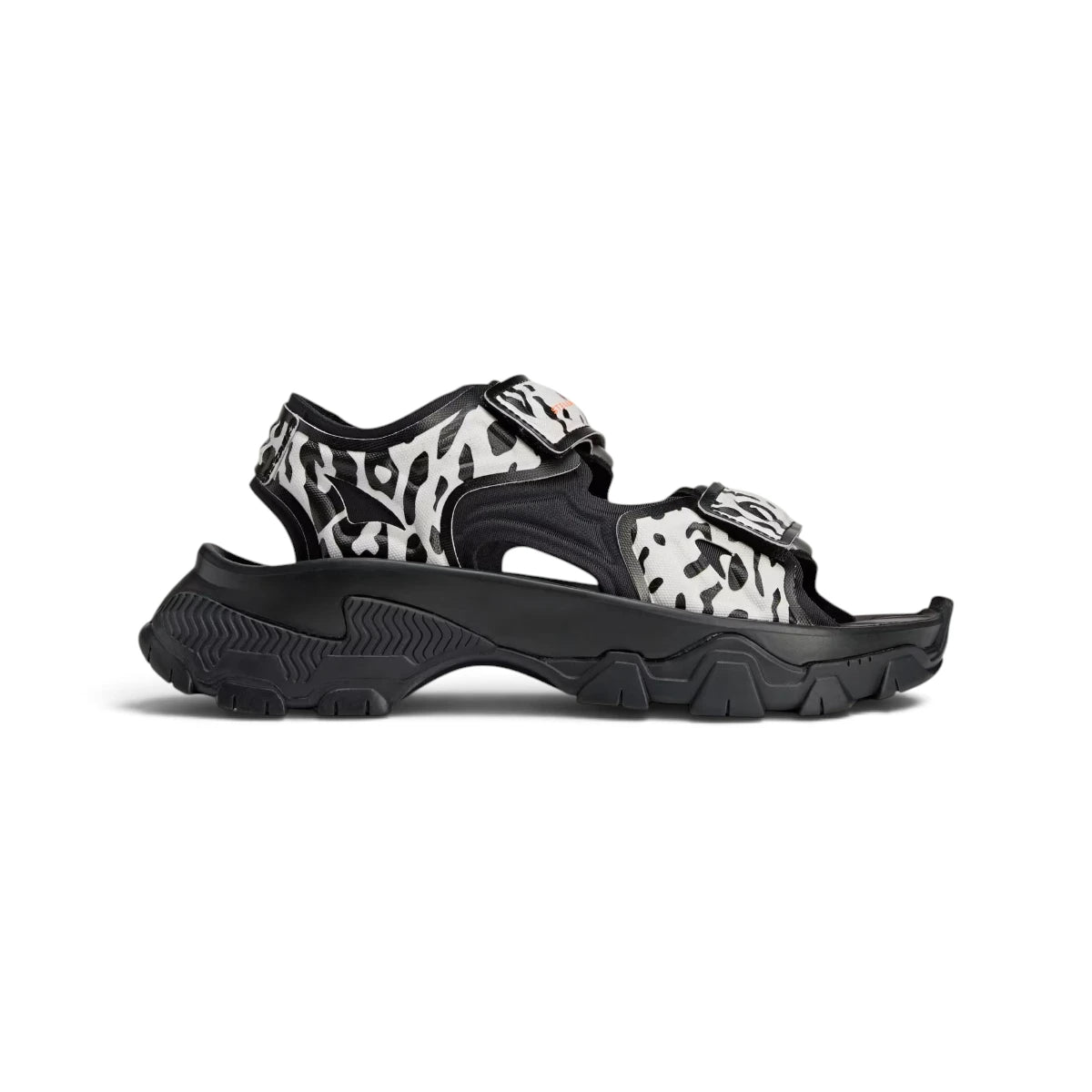 Studio side-profile shot of the adidas by Stella McCartney Hika outdoor sandals in Cloud White, Core Black, and Utility Black, highlighting the animal-print bio-synthetic straps, hook-and-loop closures, thick lightweight EVA midsole, and rugged black rubber outsole. Main image