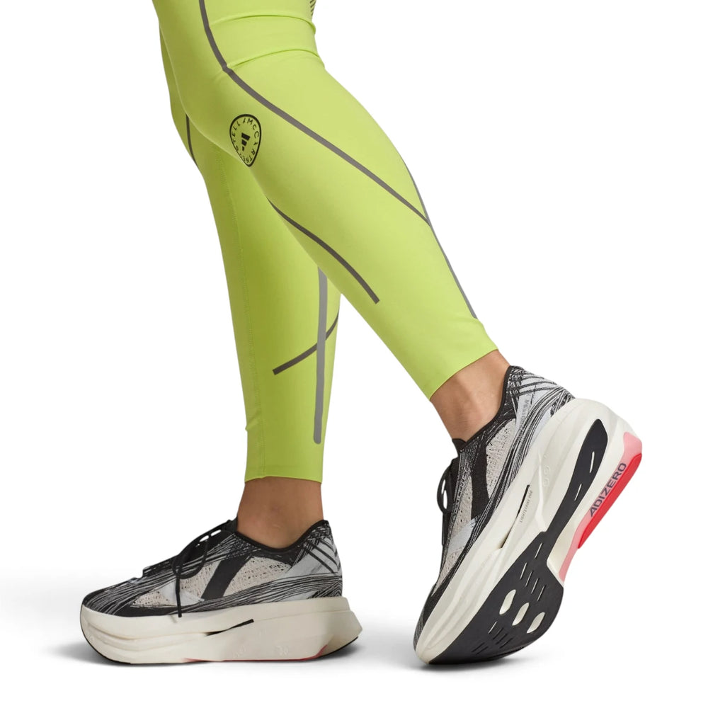 Studio lifestyle perspective of a runner wearing the shoes with neon leggings, showcasing the dynamic forward rocker shape, sleek ankle collar fit, and outsole grip.