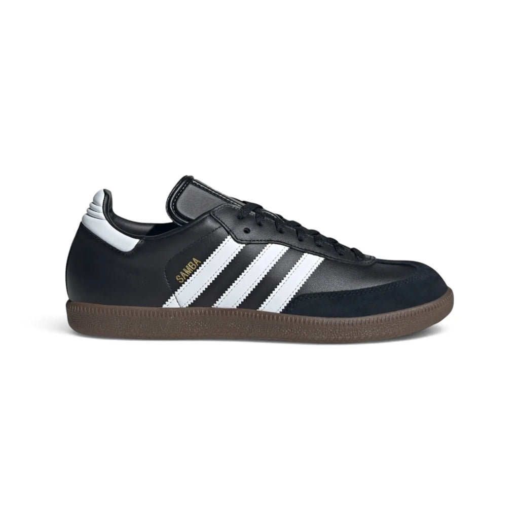 Studio lateral shot of the adidas Samba Leather Shoes in Core Black and Cloud White, highlighting the black full-grain leather upper, white serrated three stripes, gold foil SAMBA branding, suede T-toe overlay, and non-marking gum rubber outsole.
