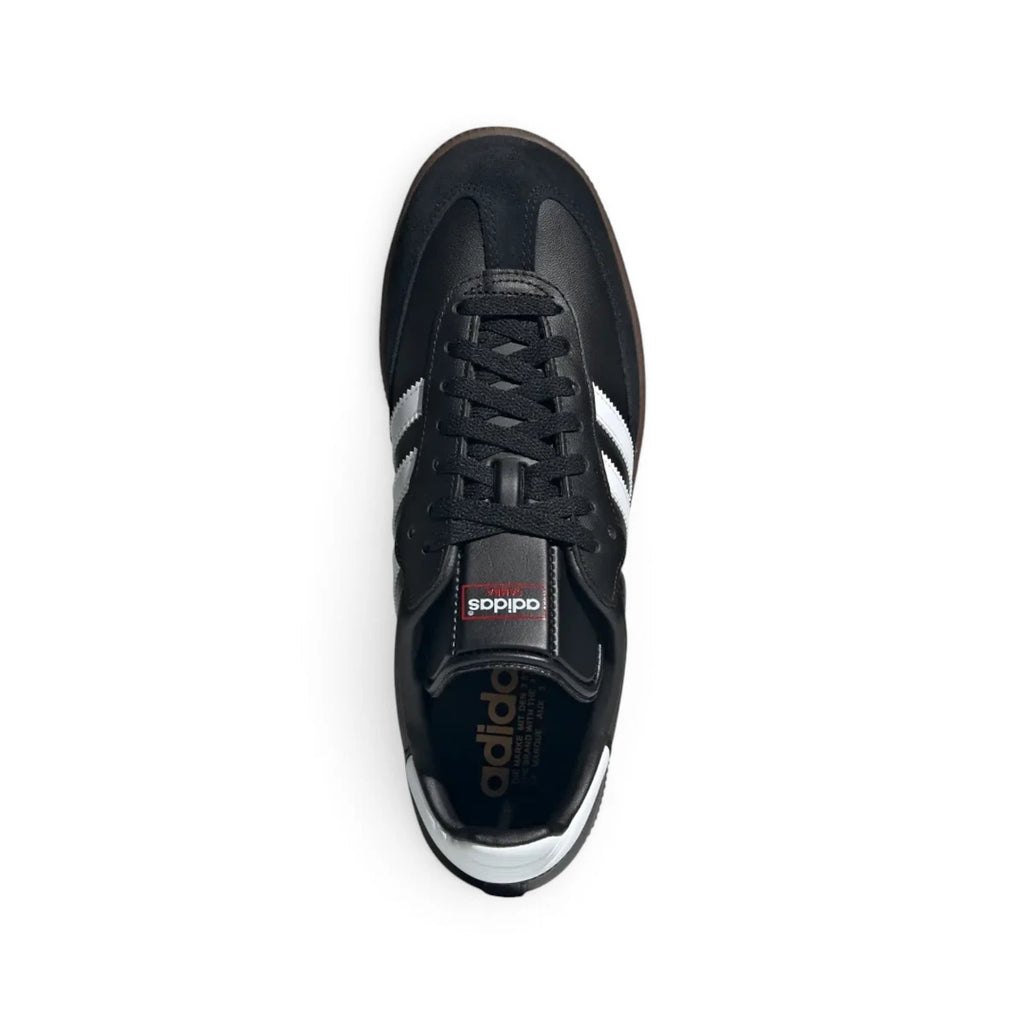 Overhead view looking down at the laced black shoes, displaying the black flat laces, elongated tongue structure featuring the classic adidas branding patch, and contrast interior lining.