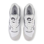 Direct overhead view of both shoes laid flat, showcasing the Brighton Grey suede toe overlay, perforated leather vamp, flat white laces threaded through reinforced eyelets, padded mesh tongue with basketball graphic crest badge, and cushioned comfort sockliner.