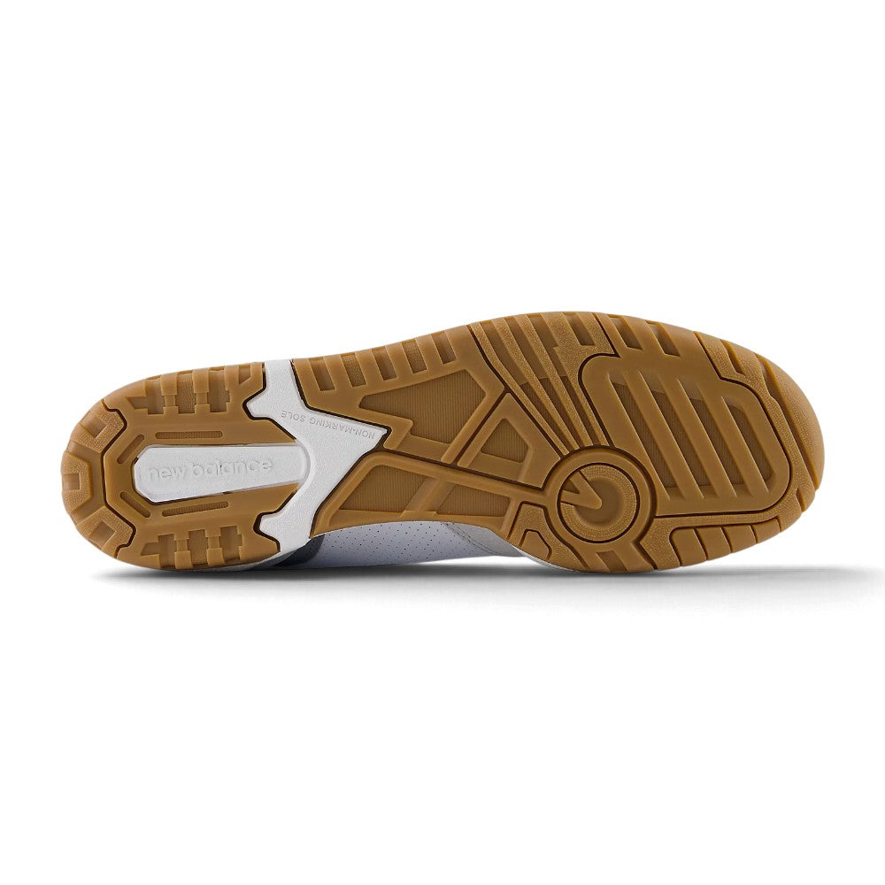 Full-length bottom profile showing the multi-directional non-marking gum rubber outsole, highlighting the circular forefoot basketball pivot ring, lateral stabiliser channels, segmented flex borders, and embossed central New Balance branding.