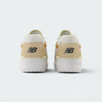Focuses on the rear profile of both heels, highlighting the tactile hairy suede heel counters, black embroidered "NB" logos, and the sturdy white rubber sole base.