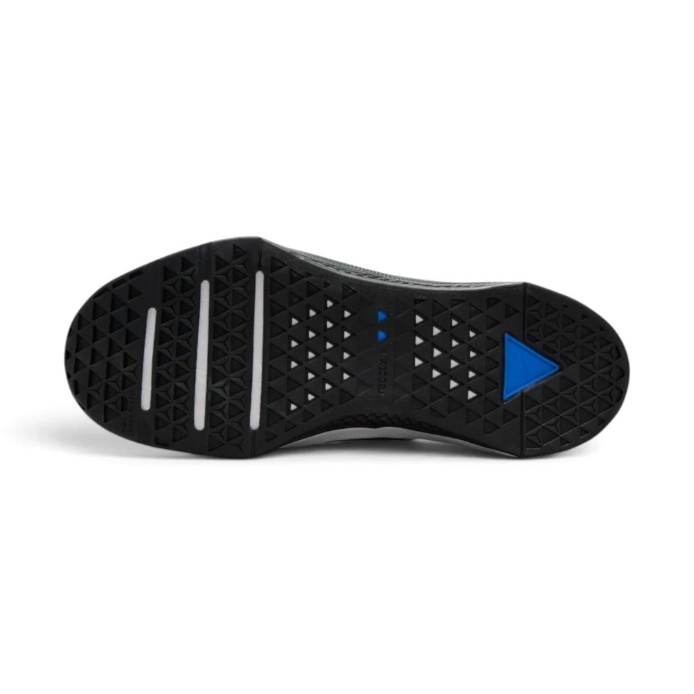 Full bottom view of the black rubber outsole, displaying multi-directional textured diamond traction patterns, white flex grooves along the forefoot, and an inset blue triangular Metcon logo insert on the heel.