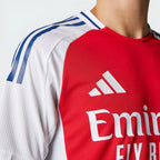 Red and white sports jersey with Adidas logo and 'Emirates' text on a plain background