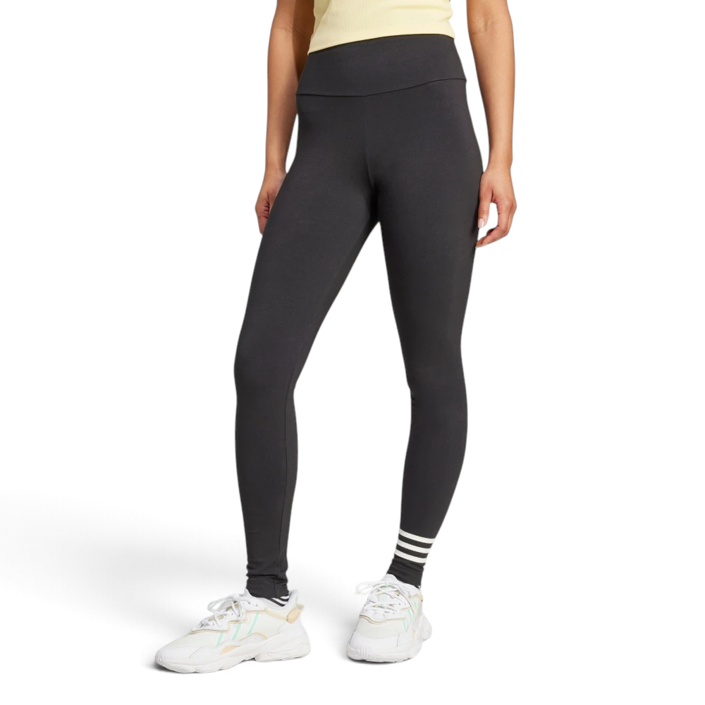 Front three-quarter view of a model wearing the black adidas Neuclassics leggings paired with white trainers, showing the high-waisted fit, full-length leg coverage, and three horizontal white stripes wrapping around the left lower shin.