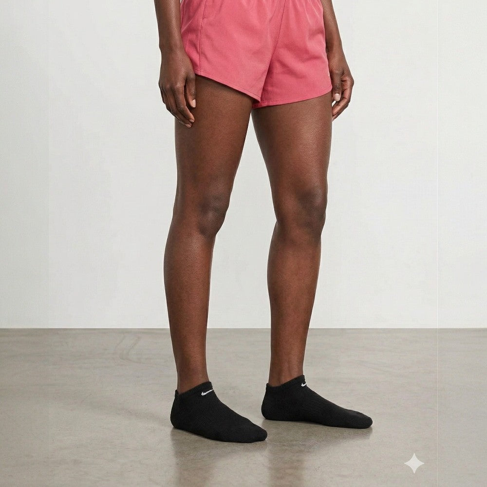 Person wearing pink shorts and black ankle socks on a plain background