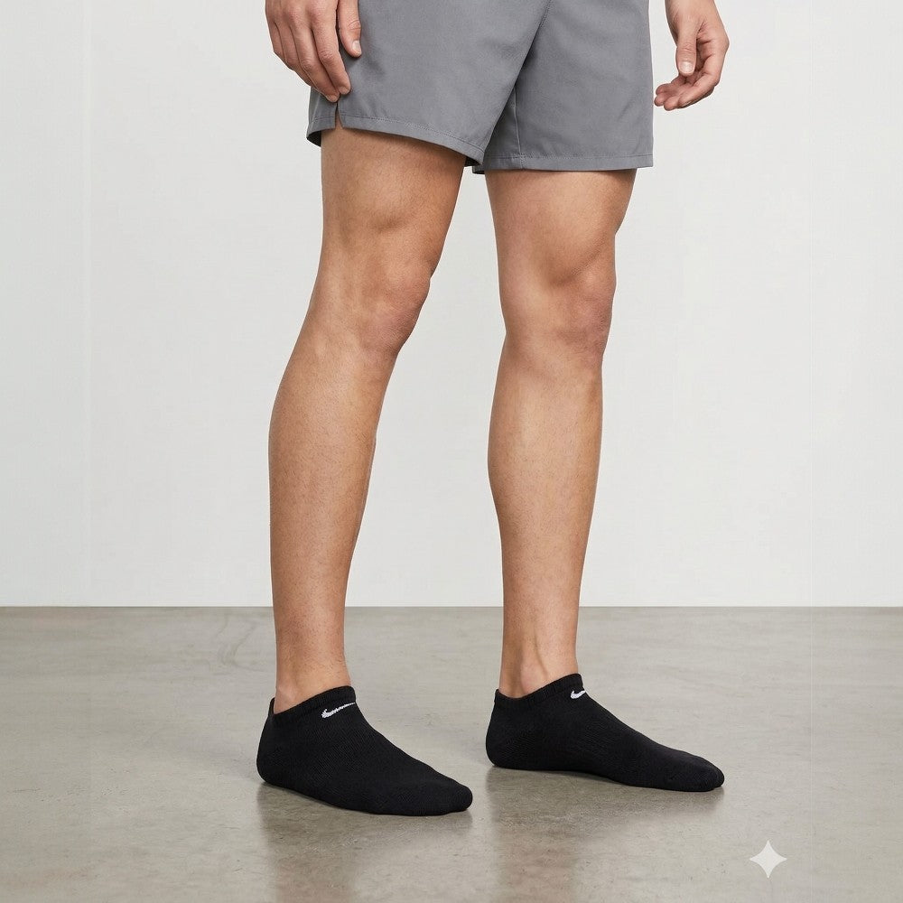 Person wearing gray shorts and black ankle socks with Nike logo on a neutral background