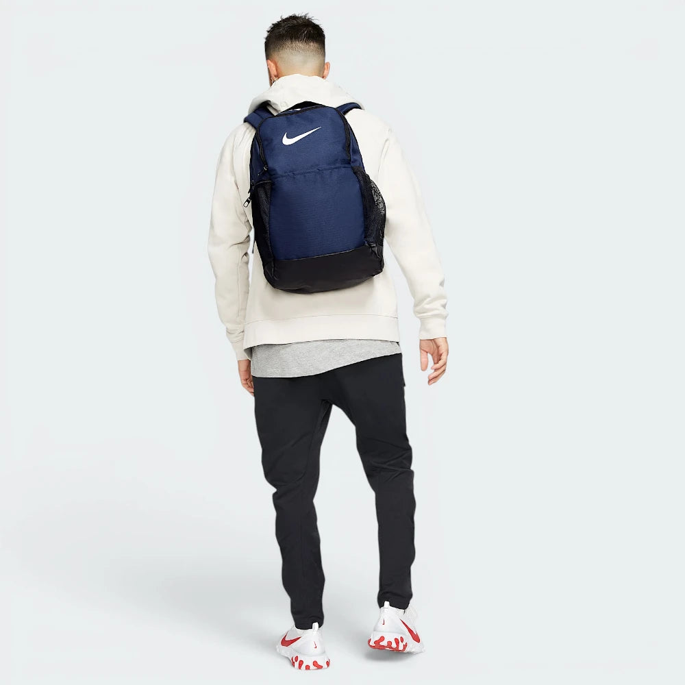 Focuses on the complete dimensional footprint of the bag, emphasizing the vibrant white corporate Nike Swoosh graphic on the front panel against the deep navy backing. Main image
