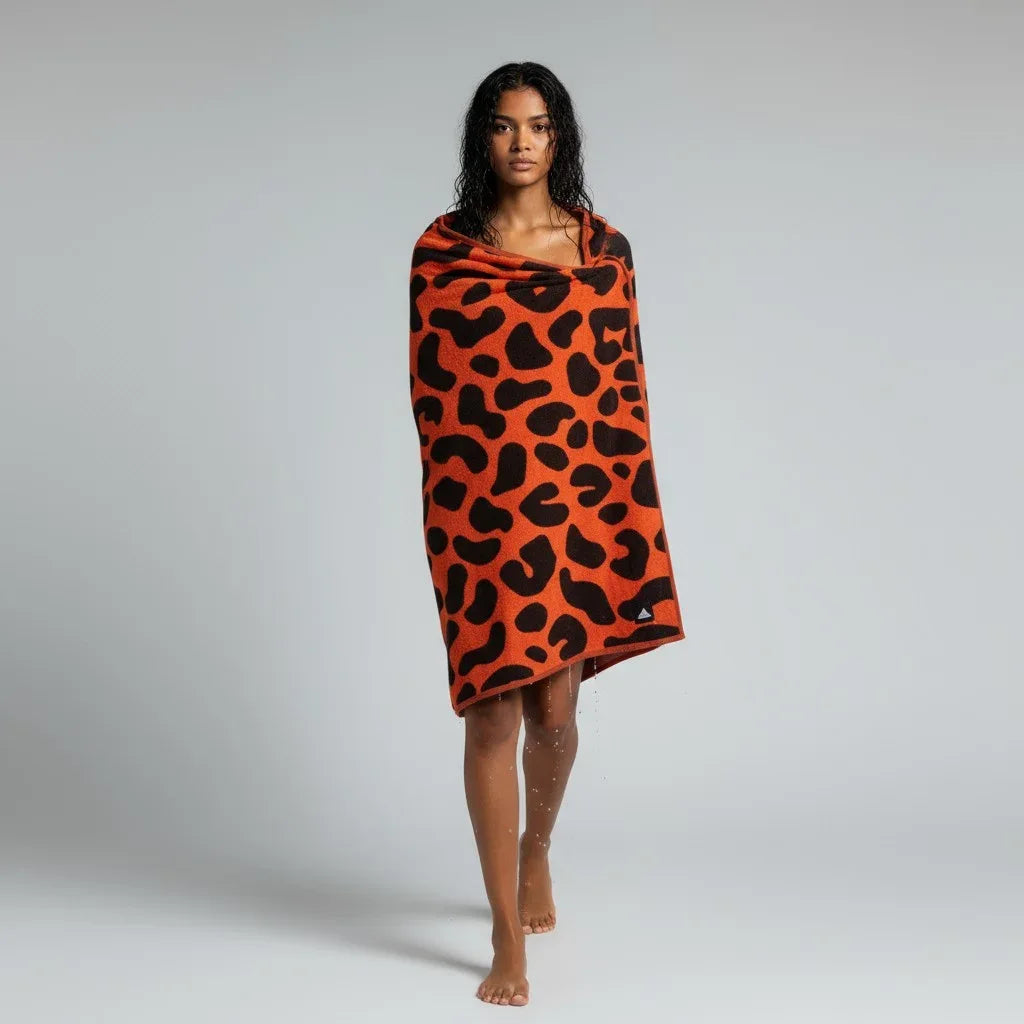 Person wearing an orange towel with black leopard print pattern on a gray background