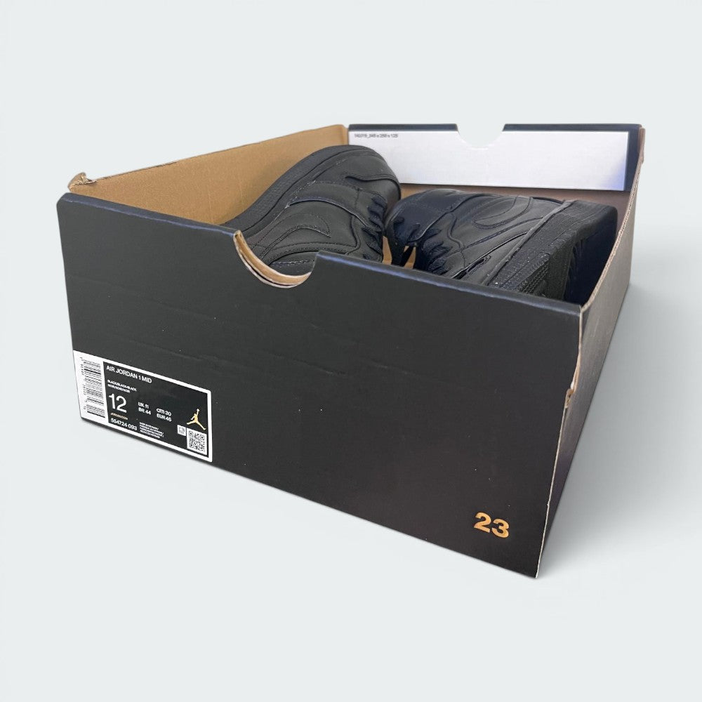 A pair of black Jordan sneakers inside an open black Air Jordan shoebox, photographed on a light gray background.