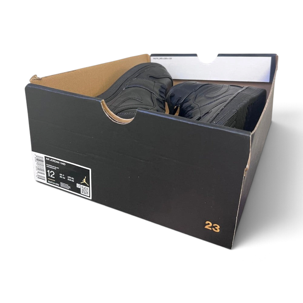 A pair of black Jordan sneakers inside an open black Air Jordan shoebox, photographed on a light gray background.