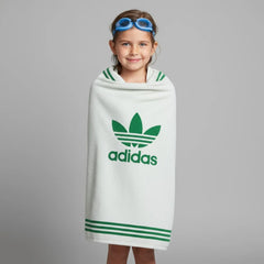Child wrapped in an Adidas towel with a gray background