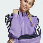 Close-up zoom on the fabric of the Adidas Tiro Track Top in purple, showing the double-knit texture and the embroidered Adidas logo.