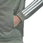 Adidas Beckenbauer Track Jacket Men's in trace green, side profile showing long sleeves with white 3-Stripes, ribbed cuffs, and regular fit.