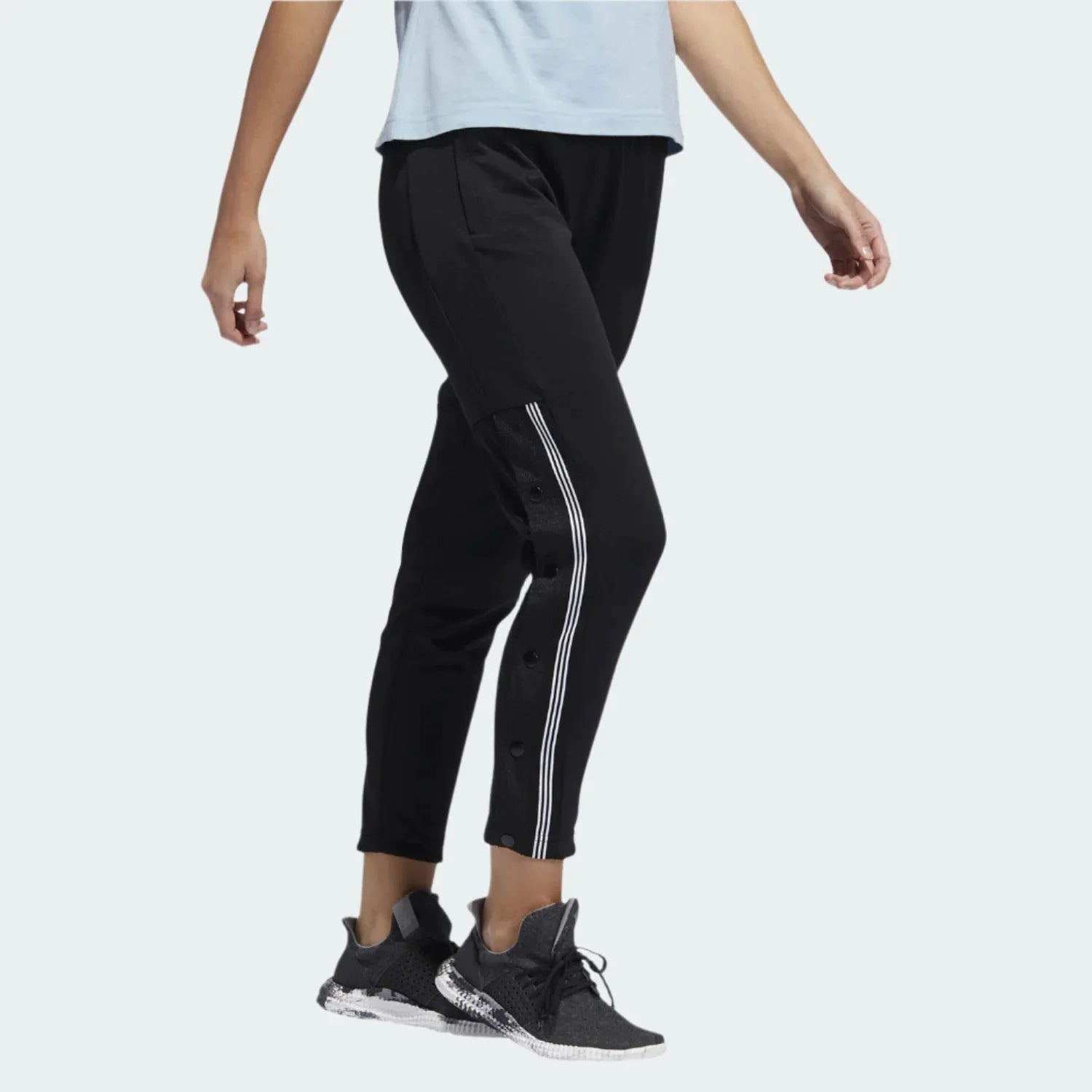 Adidas 7/8 Cropped Snap Pants Women's in black worn by a woman, showcasing the cropped length, side snap details, and relaxed fit in a casual setting. Main image