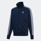 Adidas Firebird Track Jacket Men's in collegiate navy, front view showing full zip, stand-up collar, white 3-Stripes on sleeves, and Trefoil logo.