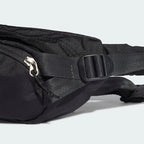 Close-up zoom on the Adidas Adventure Waist Bag in black, showing the ripstop fabric texture and the woven Adidas patch on the front.