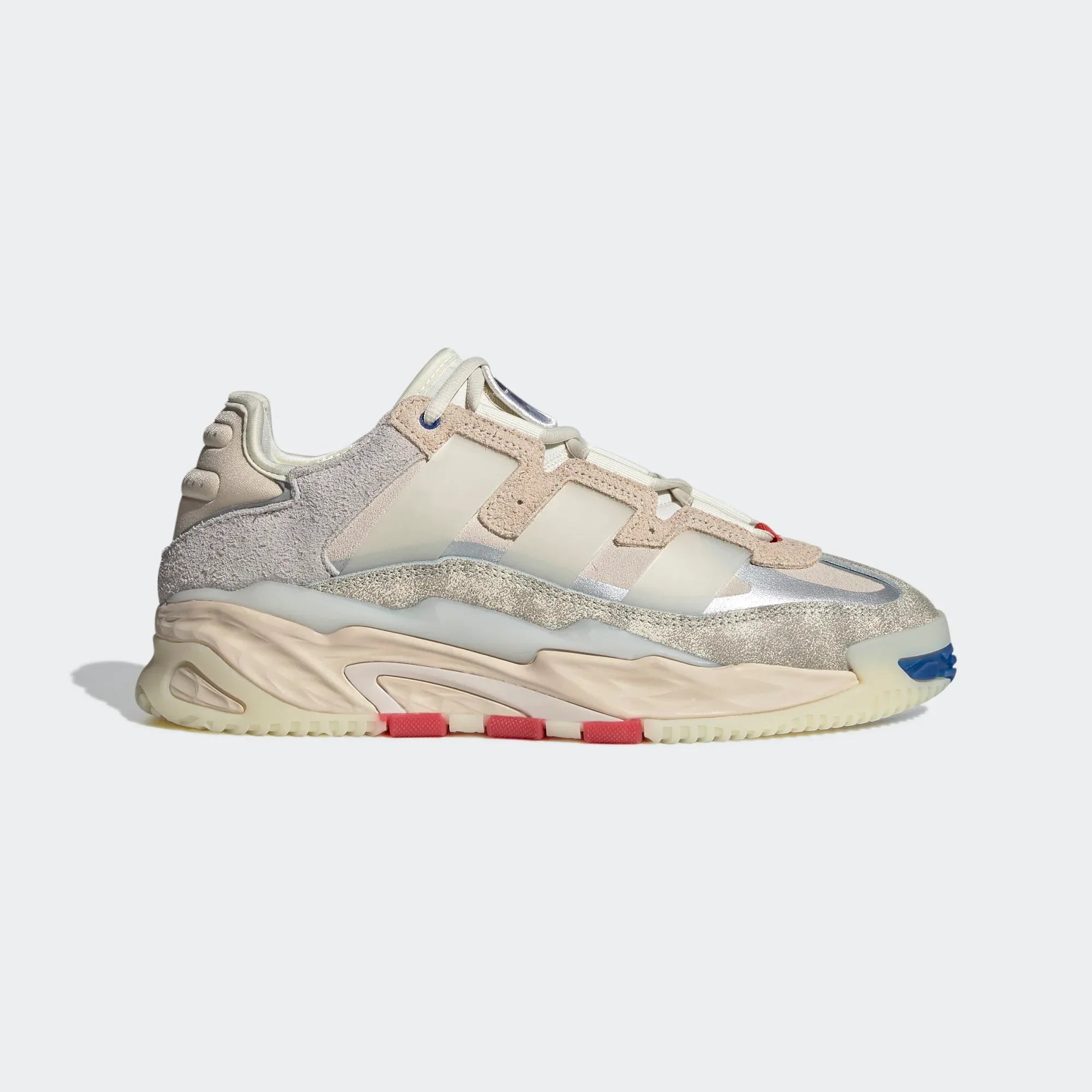 A pair of Adidas Niteball unisex sneakers with a leather upper, light misdle cushioning, and a rubber outsole, featuring a cream white color with grey, blue, and red accents.