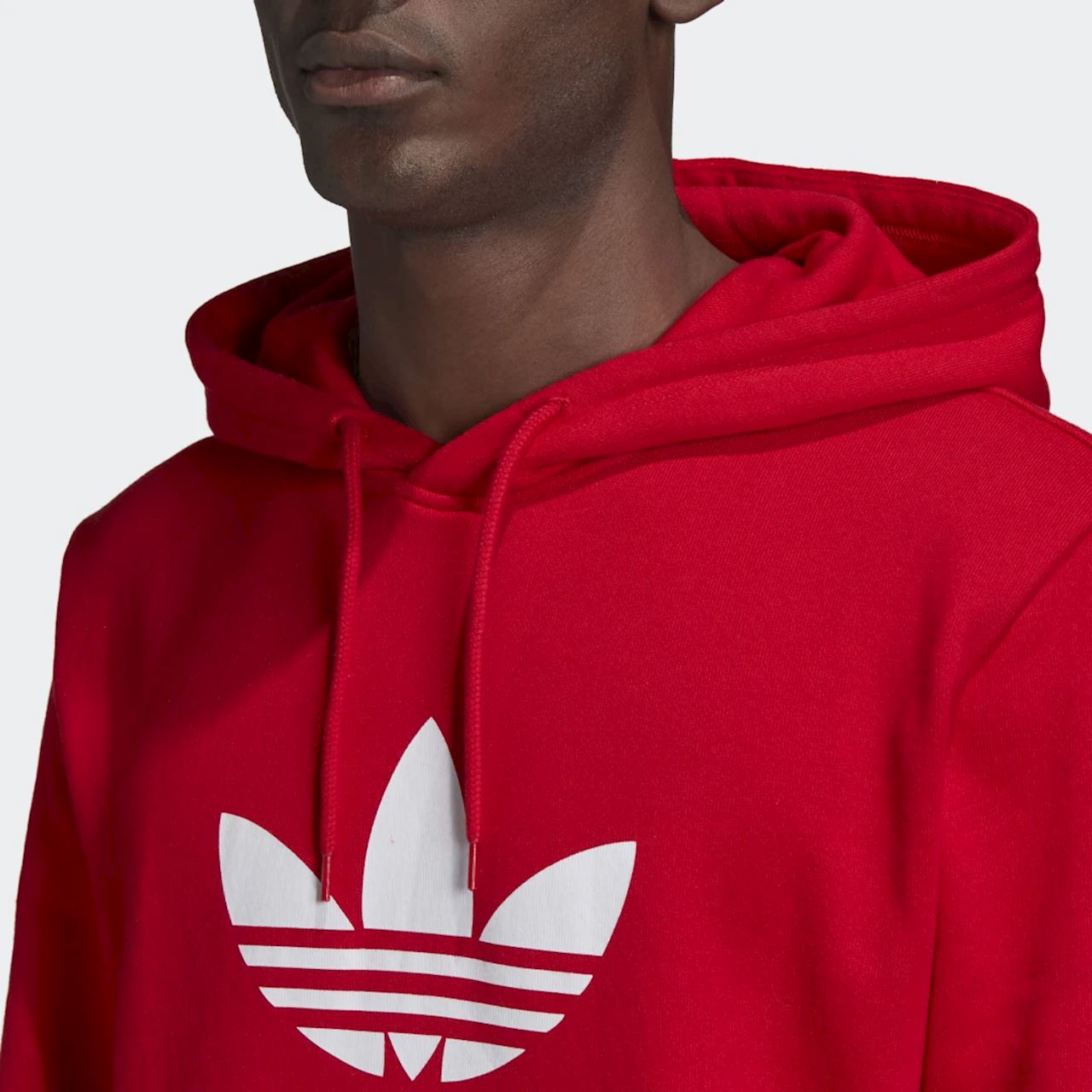 Close-up zoom on the Adidas Trefoil Hoodie Overhead Men's in red, showing the soft fleece fabric texture and the embroidered (or printed) white Trefoil logo detail.